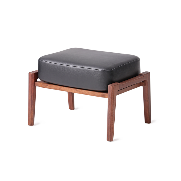 Modern ottoman with natural walnut wooden frame and black leather cushion, ideal for complementing lounge chairs in contemporary home or office decor.